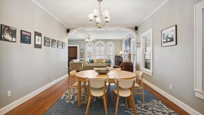A dining area with a round table, chairs, a chandelier, and a blue patterned rug. - Endless Summer by Ryson Vacation Rentals (Galveston)