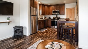 A modern kitchen with wooden cabinets, stainless steel appliances, and a stone wall.