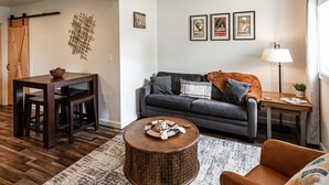 A spacious living room with a ceiling fan, a dining area with a wooden table and chairs, a gray sofa, and a coffee table.