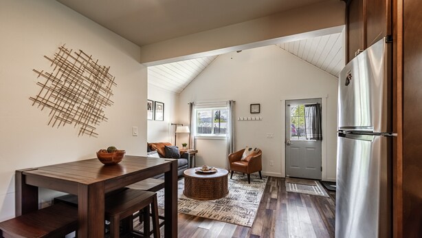 A modern kitchen with a wooden dining table, a built-in refrigerator, and a view to the outdoors.