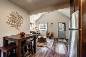 Une cuisine moderne avec une table à manger en bois, un réfrigérateur encastré et une vue sur l’extérieur.