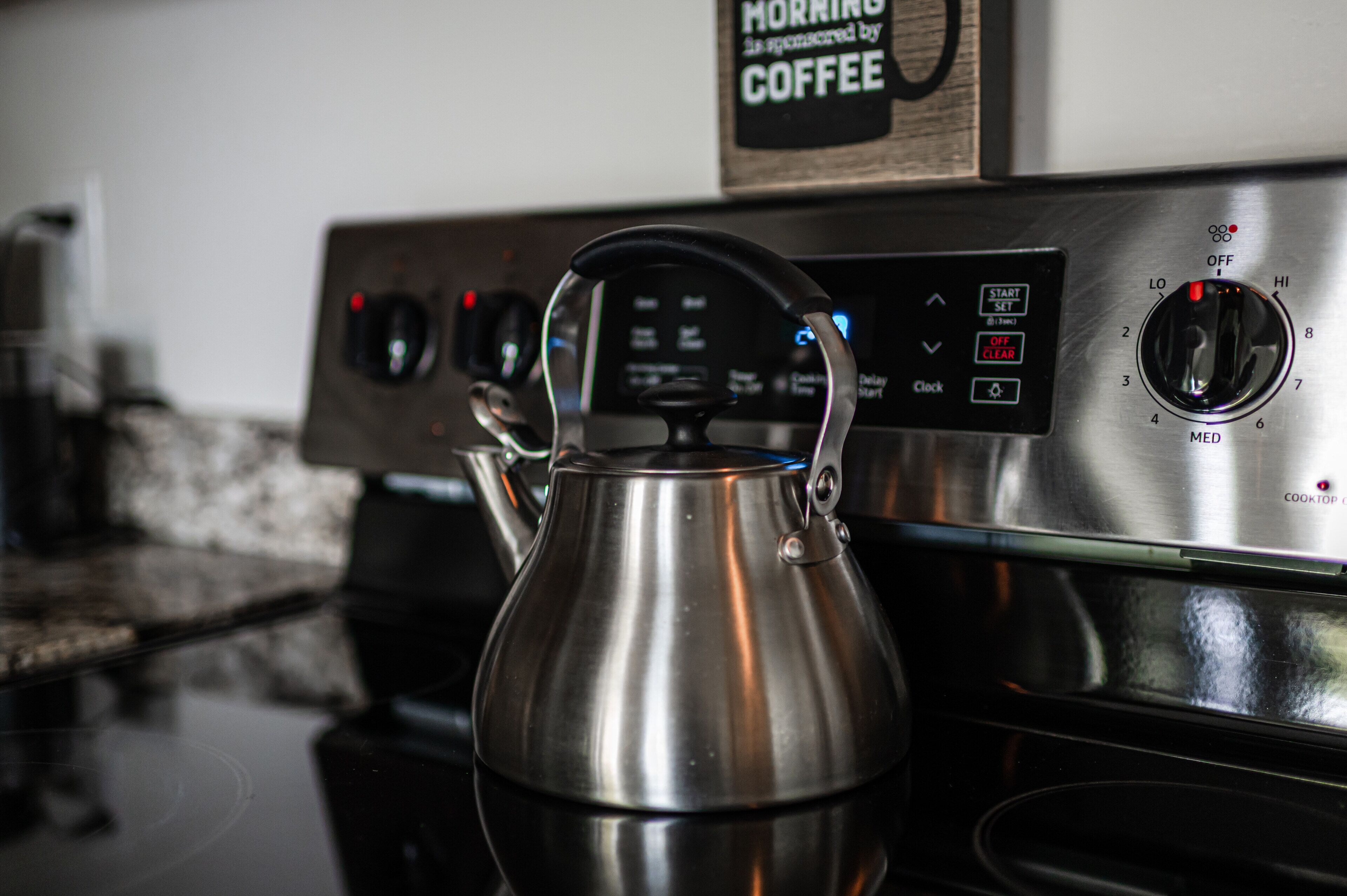 A stainless steel kettle on a stove with a digital control panel.