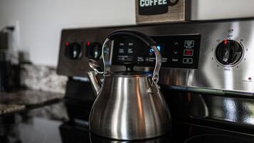 A stainless steel kettle on a stove with a digital control panel.
