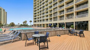 A rooftop pool area with lounge chairs, a table, and umbrellas. - Beachfront Getaway by Ryson Vacation Rentals (Galveston)