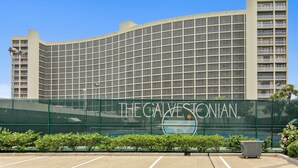 A large hotel with a curved facade and a prominent sign reading "The Galvestonian." - Beachfront Getaway by Ryson Vacation Rentals (Galveston)