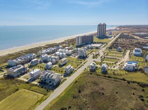 An aerial view of a coastal residential area with beachfront properties, a large hotel, and a golf course.
