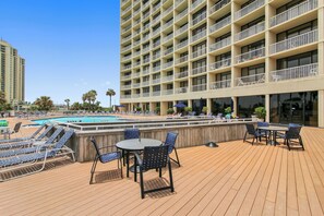 A rooftop pool area with lounge chairs, a table, and umbrellas.
