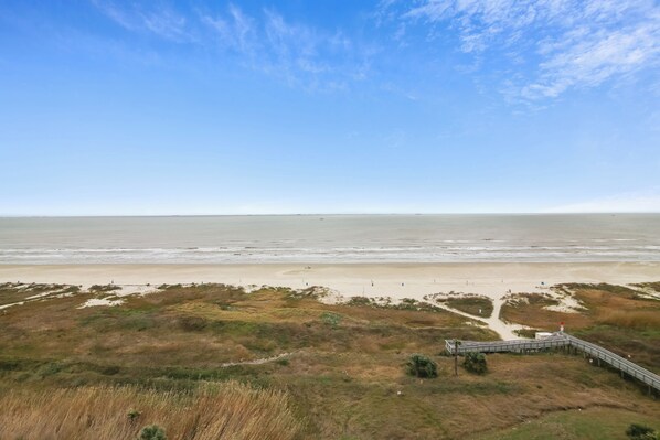 Une plage avec une promenade en bois qui mène à une zone de dunes.