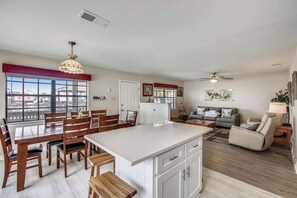 A spacious kitchen with a large island, dining area, and a living room with a sofa and chairs. - Herons Nest by Ryson Vacation Rentals (Galveston)