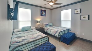 A bedroom with two beds, a ceiling fan, and a window with blinds. - Honu Beachfront by Ryson Vacation Rentals (Galveston)