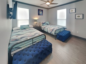 A bedroom with two beds, a ceiling fan, and a window with blinds. - Honu Beachfront by Ryson Vacation Rentals (Galveston)