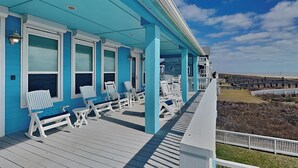 A covered outdoor area with white lounge chairs and a view of the beach. - Honu Beachfront by Ryson Vacation Rentals (Galveston)
