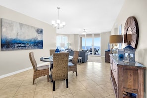 A dining area with wicker chairs, a round table, and a view to the outside.