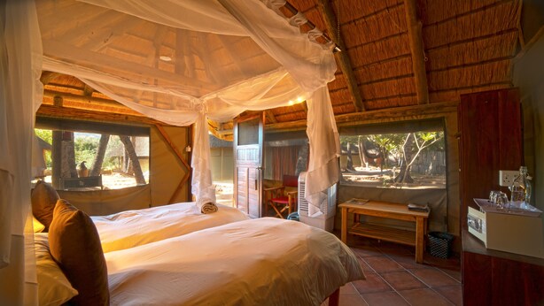 Een kamer met een bed, een bankje en uitzicht op het landschap.