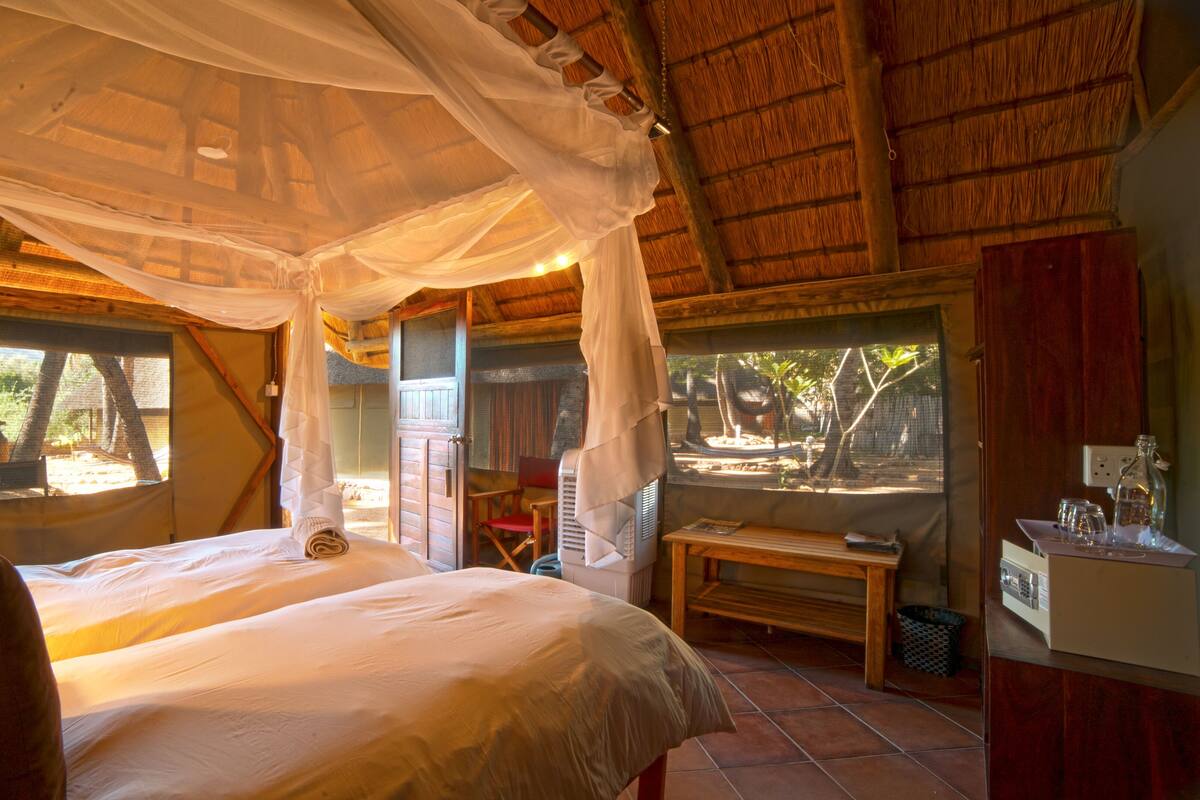A room with a bed, a bench, and a view of the outdoors.