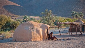 Een woestijnlandschap met een grote, koepelvormige constructie en een kleinere hut.