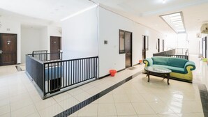 A spacious hallway with a black metal railing, a teal sofa, and a glass coffee table. - OYO Flagship 90524 Holistay Surabaya New (Surabaya)