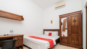 A hotel room with a bed, a desk, a chair, a wardrobe, and an air conditioning unit. - OYO Flagship 90524 Holistay Surabaya New (Surabaya)