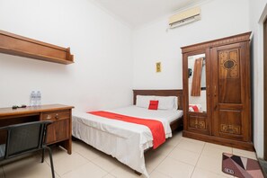 A hotel room with a bed, a desk, a chair, a wardrobe, and an air conditioning unit. - OYO Flagship 90524 Holistay Surabaya New (Surabaya)