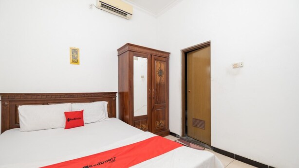 A hotel room with a bed, a wardrobe, and a door. - OYO Flagship 90524 Holistay Surabaya New (Surabaya)