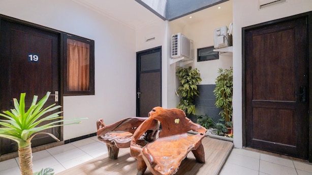 A modern interior with a wooden bench, a potted plant, and a door labeled '19'. - OYO Flagship 90524 Holistay Surabaya New (Surabaya)