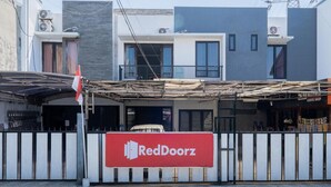 A RedDoorz storefront with a metal fence and a flag. - OYO Flagship 90524 Holistay Surabaya New (Surabaya)