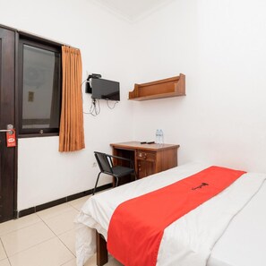 Ein Hotelzimmer mit einem Bett, einem Schreibtisch, einem Sessel, einem an der Wand montierten Fernseher und einem Holzboden.