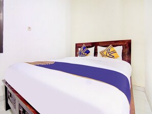 A bed with a wooden headboard, white bedding, and decorative pillows with geometric patterns. - Spot ON 90152 Garuda Bima Residence Syariah (Tangerang)