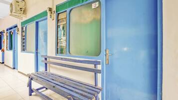 Una fila de puertas azules con un banco delante, un ventilador de techo y piso de baldosas.