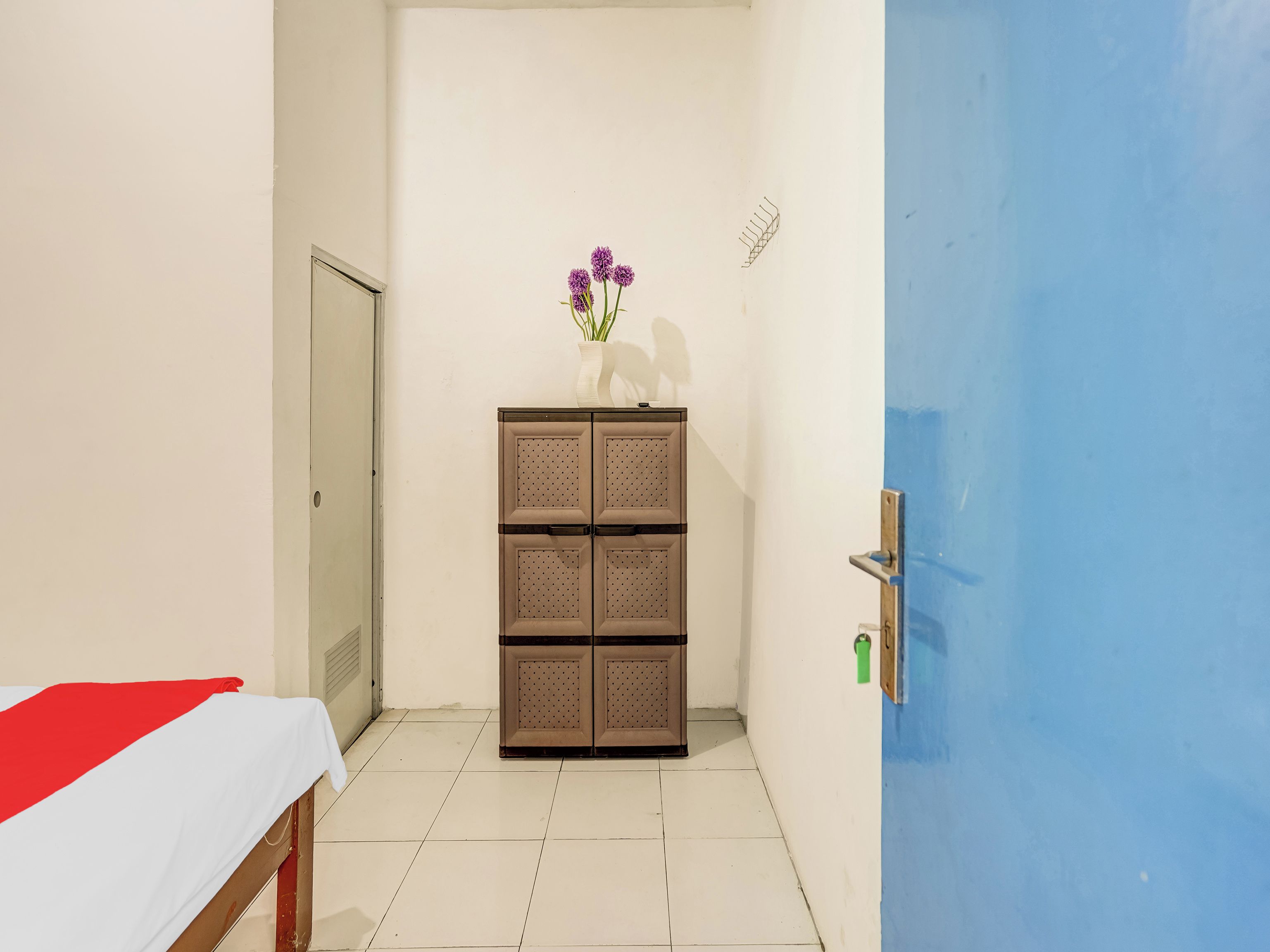 Habitación de hotel con cama, armario y puerta azul.