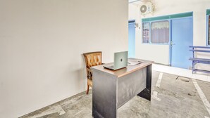 A room with a desk, a chair, and a laptop. There is a blue door and a window with a view of the outside. - OYO 90523 Homestay Jenggolo (Sidoarjo)