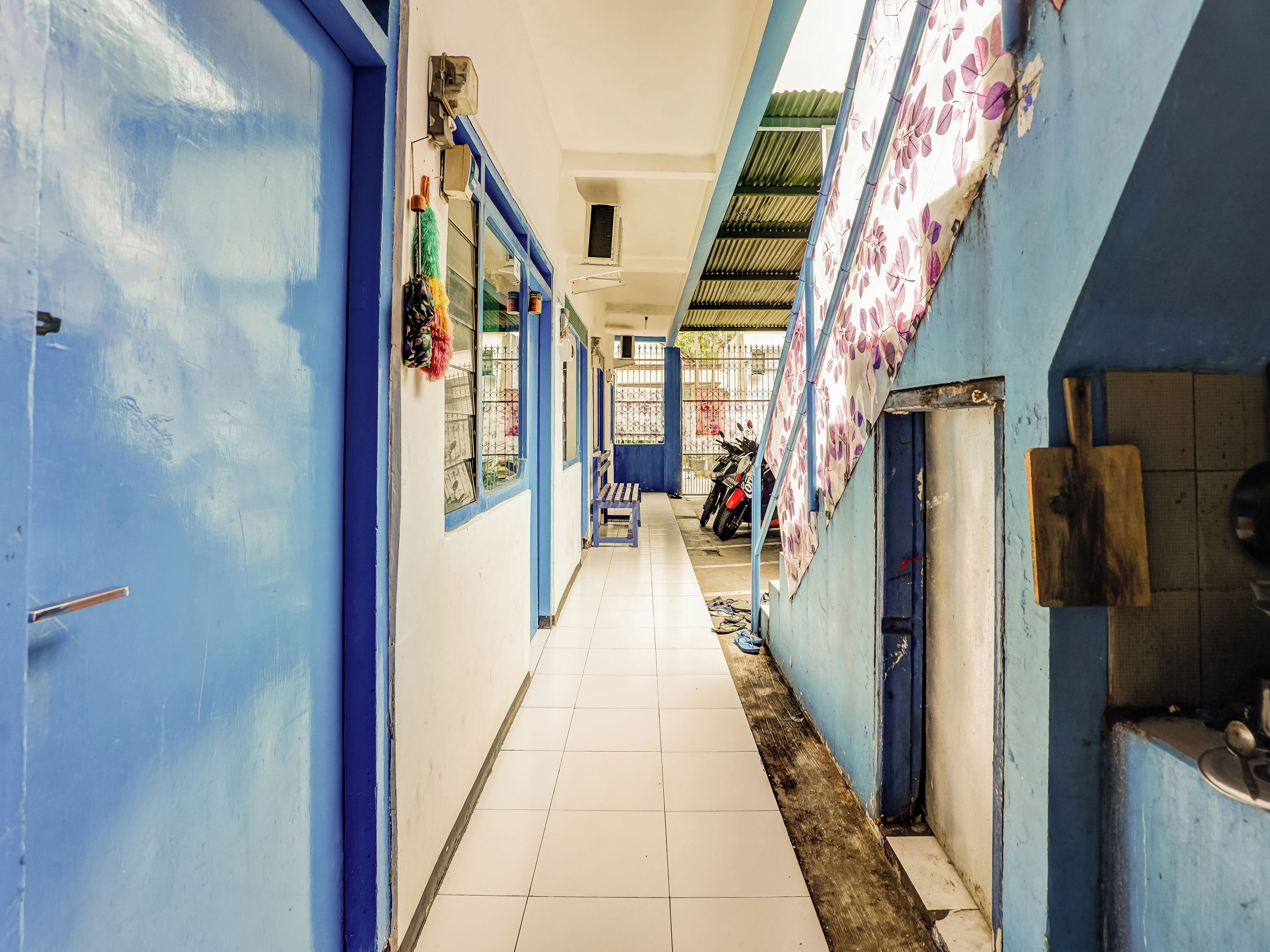 A corridor with blue walls, tiled flooring, and a motorcycle parked at the end.