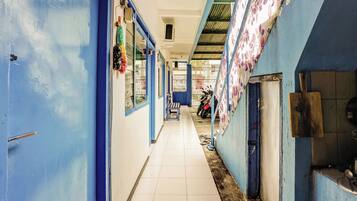 A corridor with blue walls, tiled flooring, and a motorcycle parked at the end.