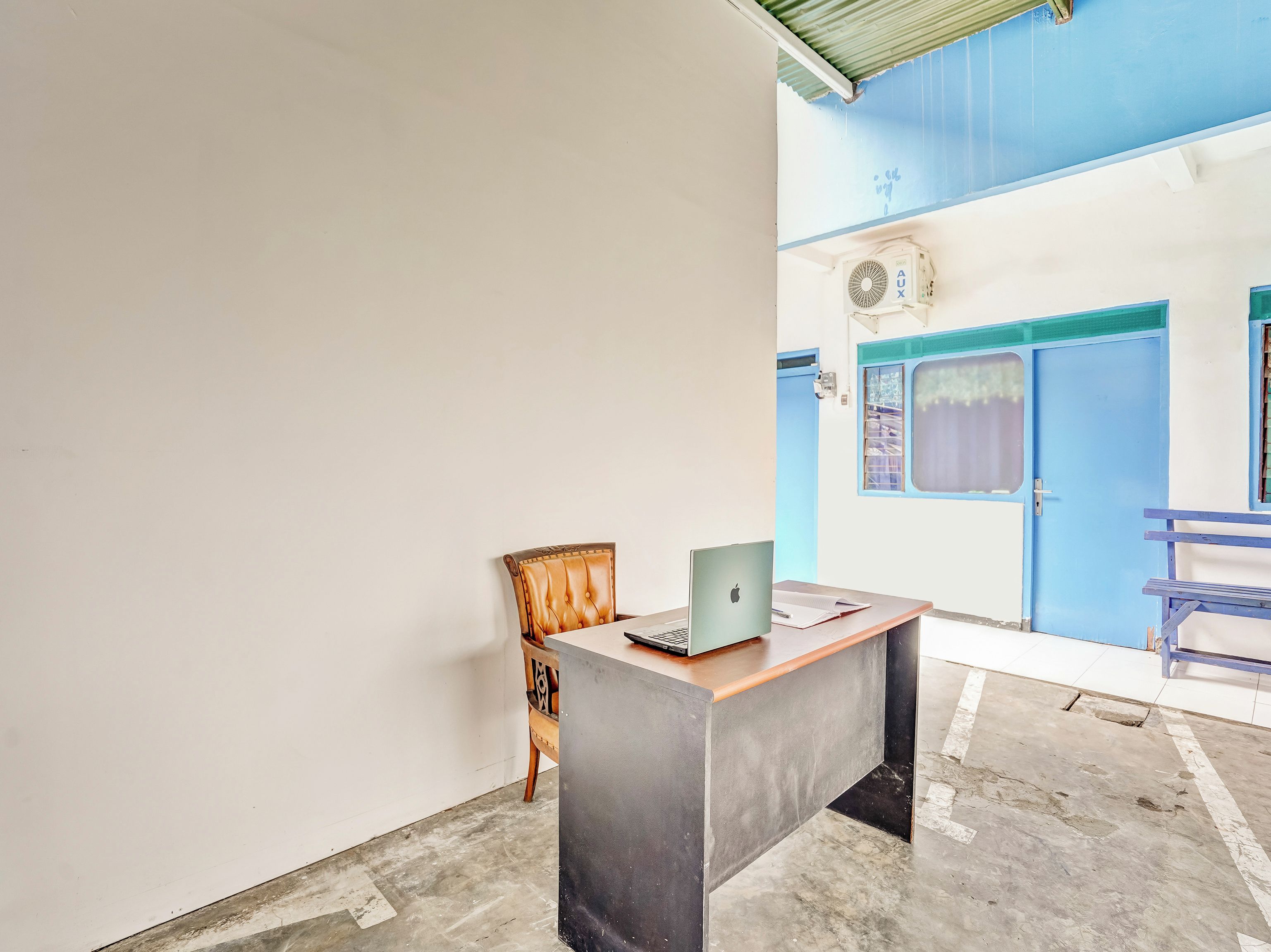 Una habitación con escritorio, silla, computadora portátil y ventana con vistas al exterior.