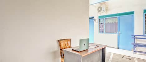 A room with a desk, a chair, a laptop, and a window with a view of the outside.