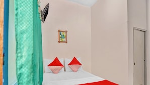 A neatly made bed with a white and red patterned bedspread, two red pillows, and a small framed book on the wall. - OYO 90523 Homestay Jenggolo (Sidoarjo)