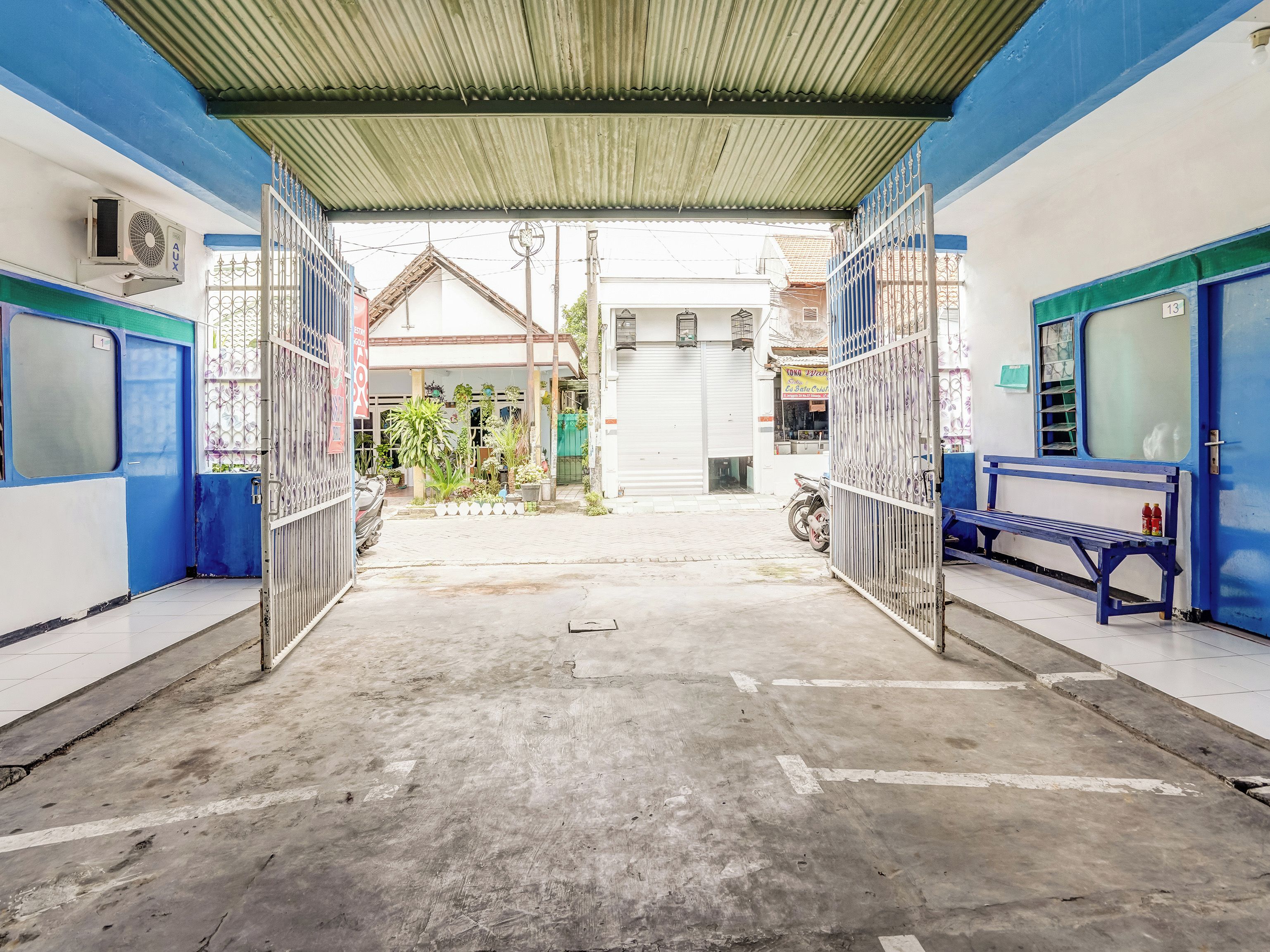 A covered walkway with metal gates, a bench, and a small garden area.
