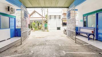 A covered walkway with metal gates, a bench, and a small garden area.