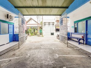 A covered walkway with metal gates, a bench, and a small garden area.