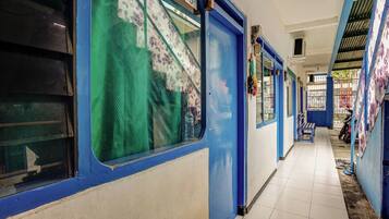 A corridor with blue doors and windows, tiled floor, and a bench.