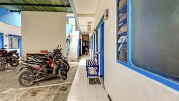 Una estación de tren con piso de baldosas, paredes azul y blanco, y una zona techada con motocicletas estacionadas.
