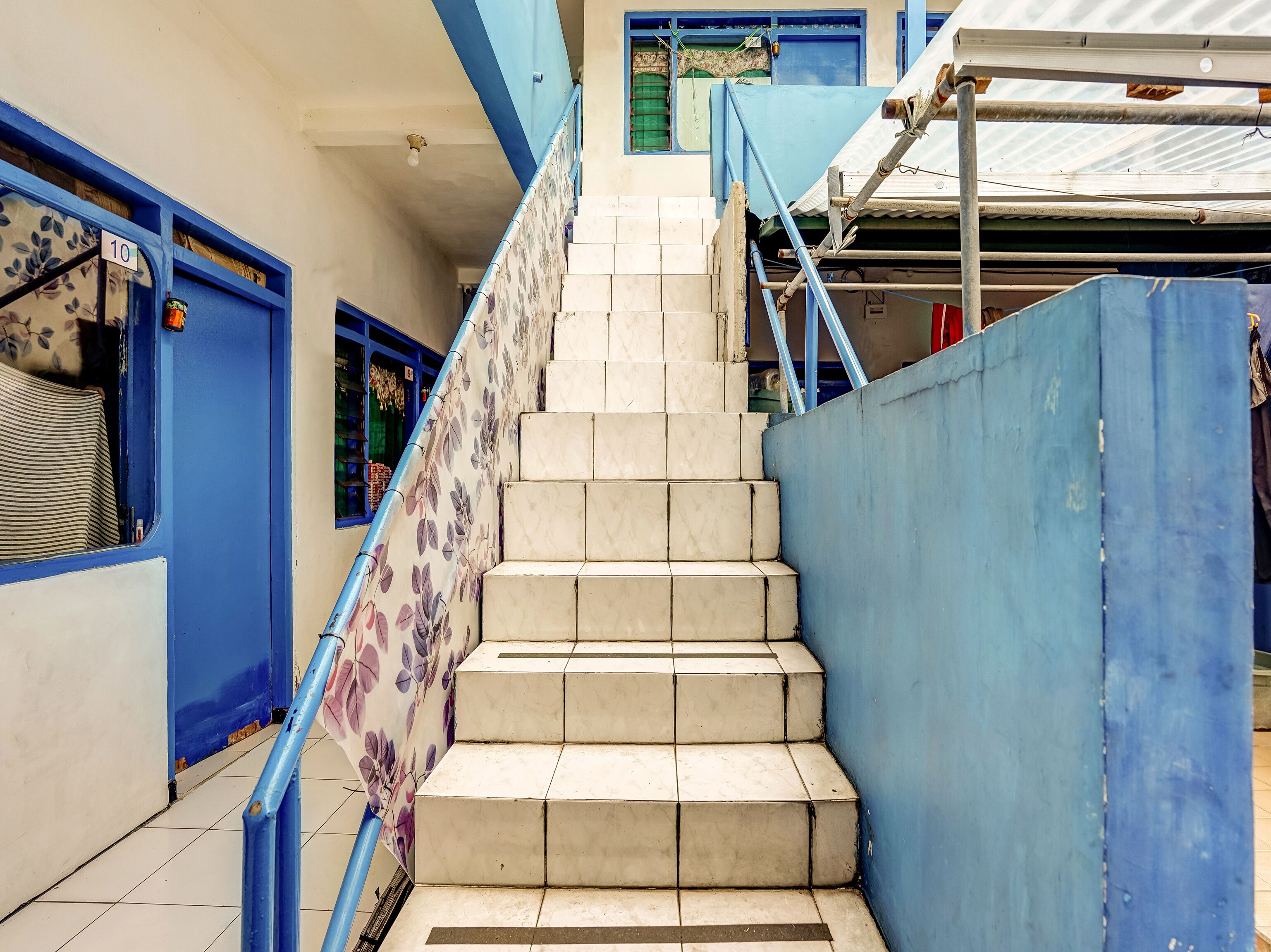 Una escala amb baranes blaves i un mur amb un dibuix floral.