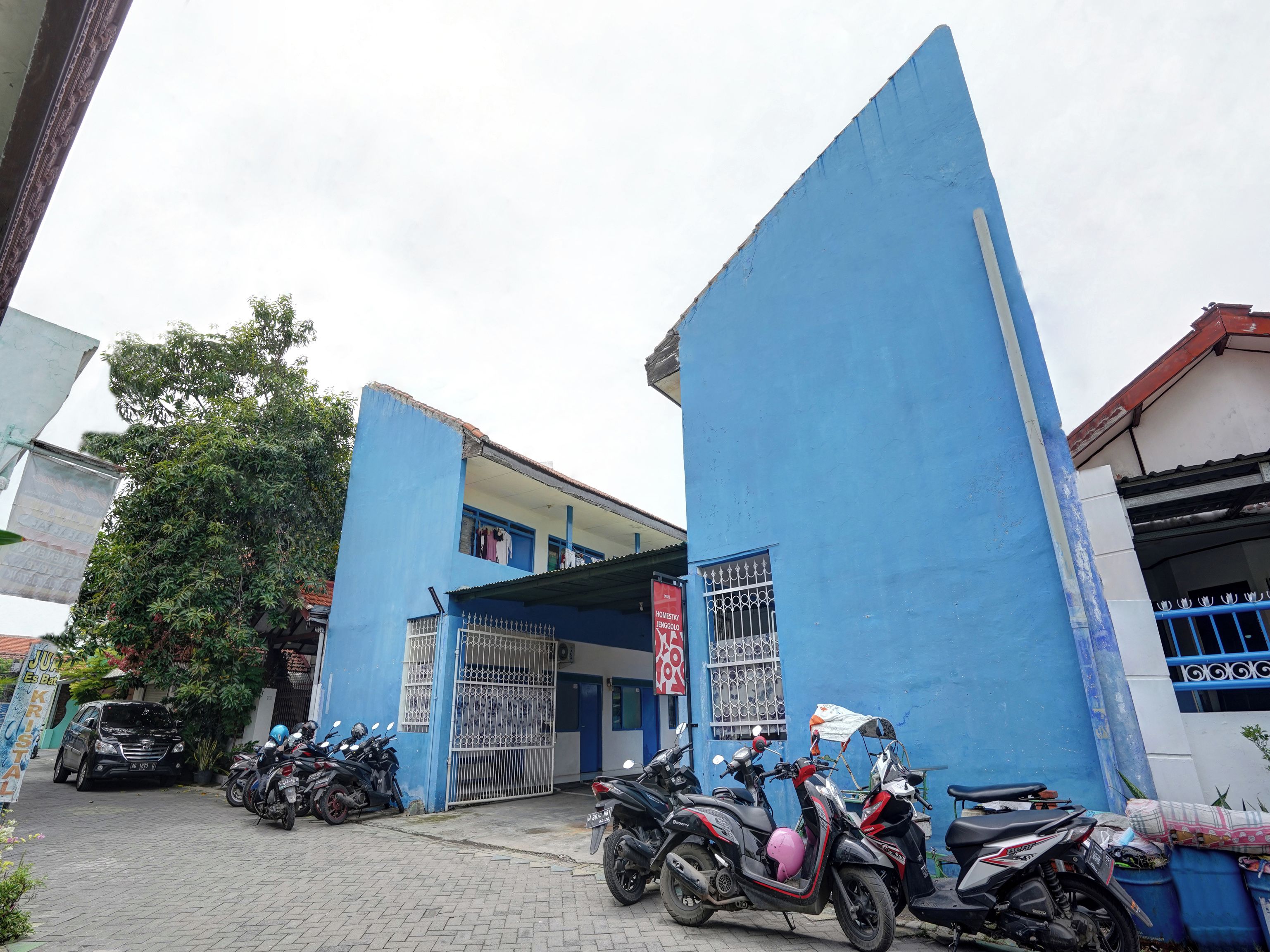 Un edificio con fachada azul, entrada protegida por una reja y varias motocicletas estacionadas.