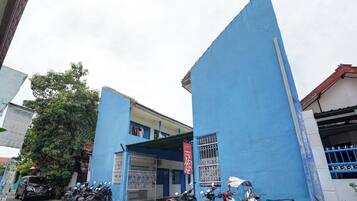 Un edificio con fachada azul, entrada protegida por una reja y varias motocicletas estacionadas.