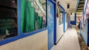 A corridor with blue and white walls, a tiled floor, and a window with a floral pattern. - OYO 90523 Homestay Jenggolo (Sidoarjo)