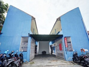 A building entrance with a blue facade, metal gates, and parked motorcycles.