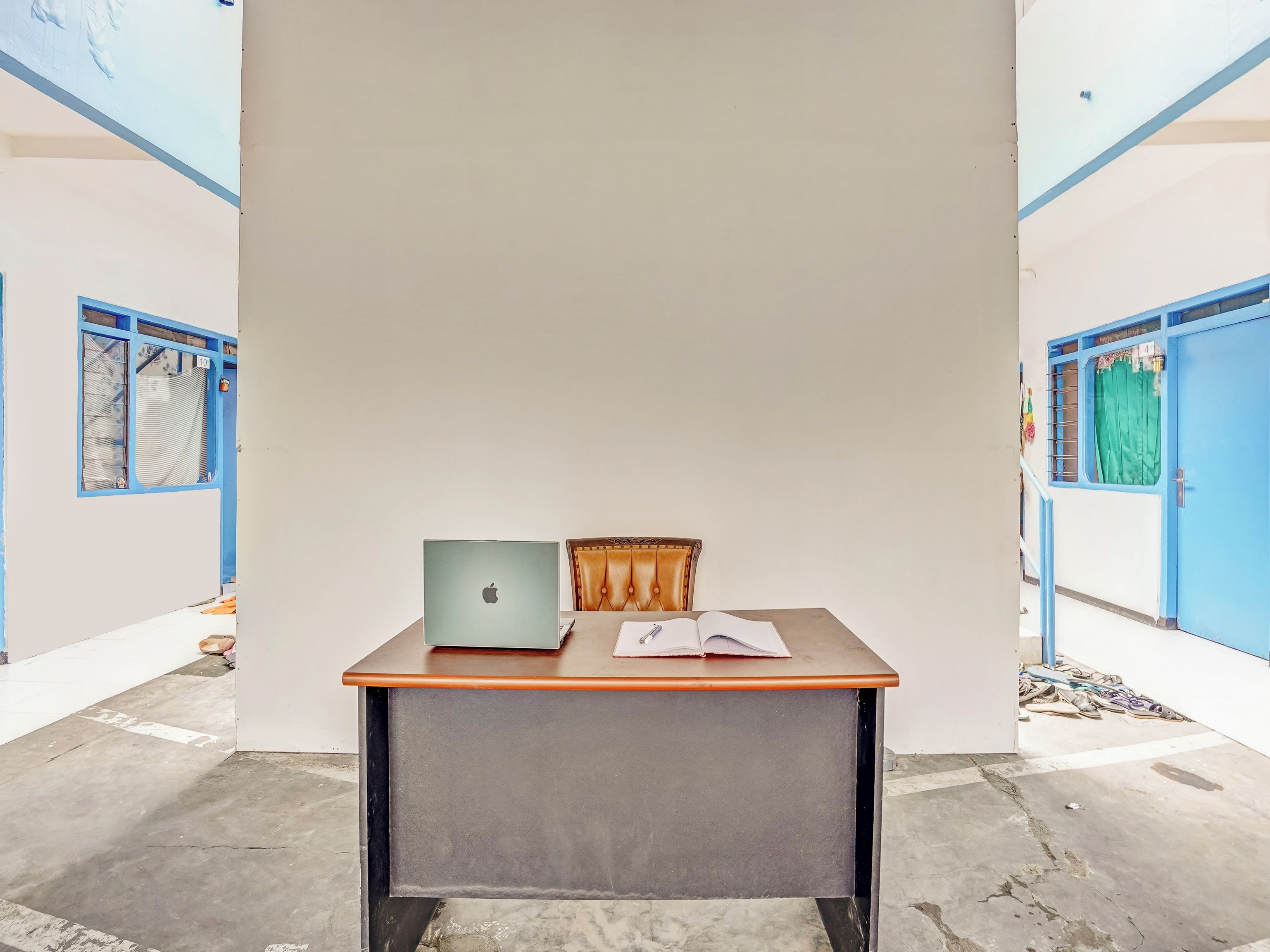 A room with a desk, a laptop, and a chair.