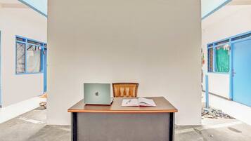 A room with a desk, a laptop, and a chair.