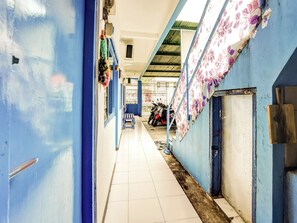 A corridor with blue walls, a tiled floor, and a motorcycle parked at the end. - OYO 90523 Homestay Jenggolo (Sidoarjo)