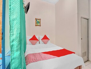 A hotel room with a bed, a television mounted on the wall, and a door. - OYO 90523 Homestay Jenggolo (Sidoarjo)